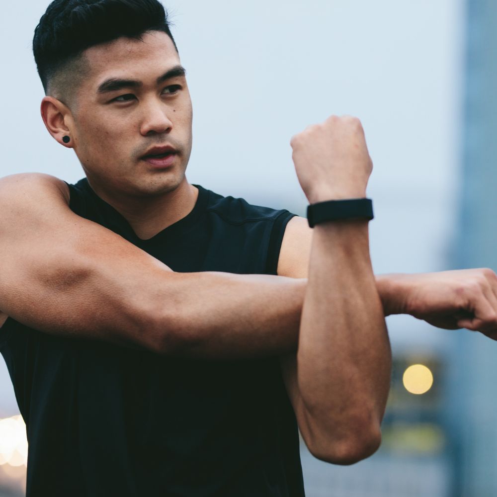 Man flexing his arm muscles outdoors with a blurred background