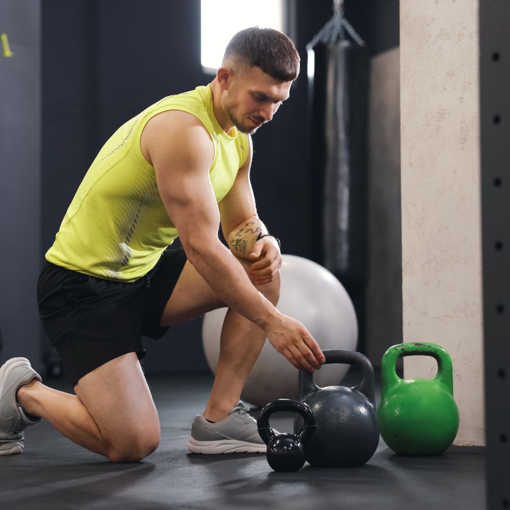 Man preparing to lift kettlebells in a gym setting